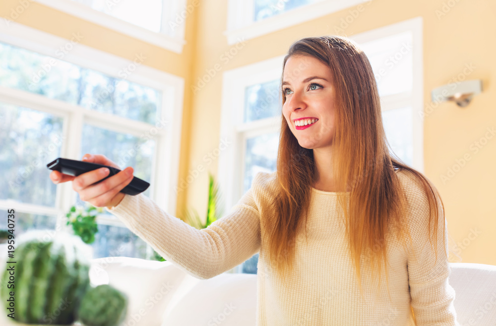 Young woman watching with remote control watching TV in the living room