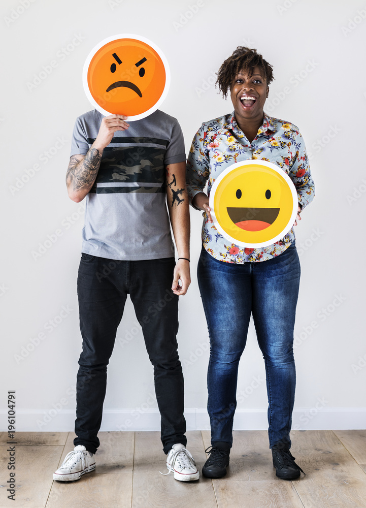 Interracial couple holding an expressive emoticon face facial expression frown and smile relationshi