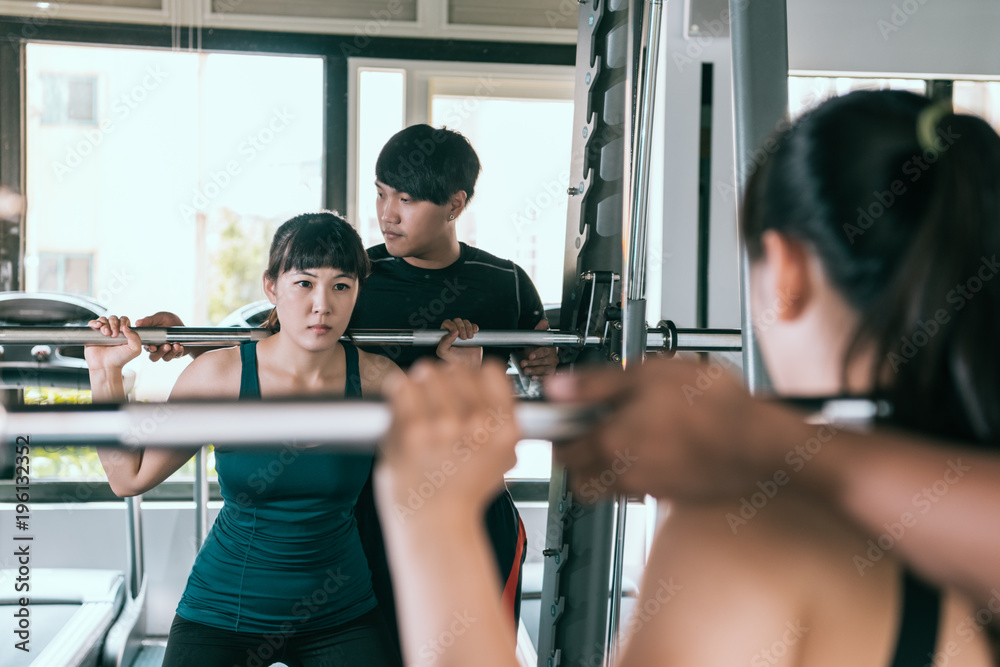 女子与私人教练一起做深蹲