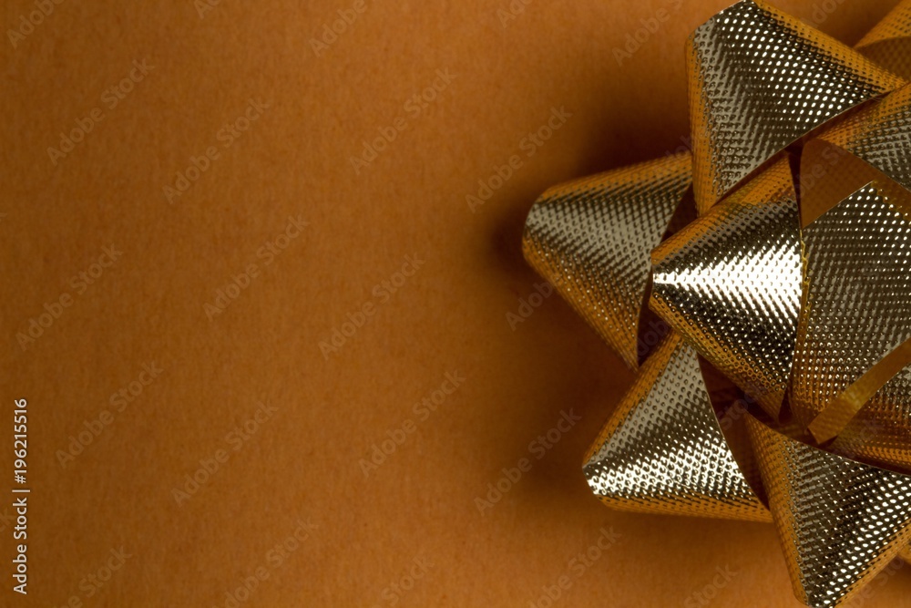 Golden wrapping paper with a shiny gold bow on top