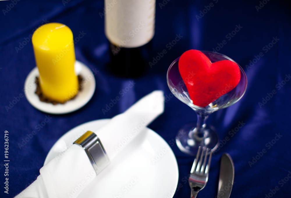 Romantic table setting with wine, heart and a candle