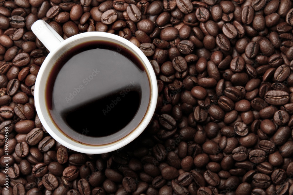 Cup of coffee surrounded by coffee beans