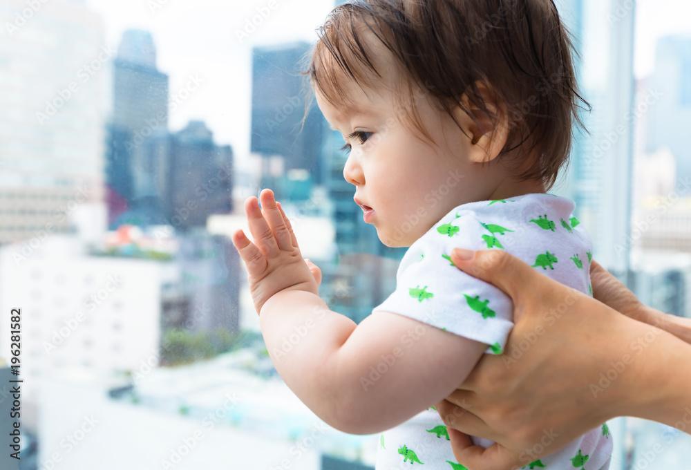 Toddler boy looking out at Downtown Los Angeles from a glass balcony