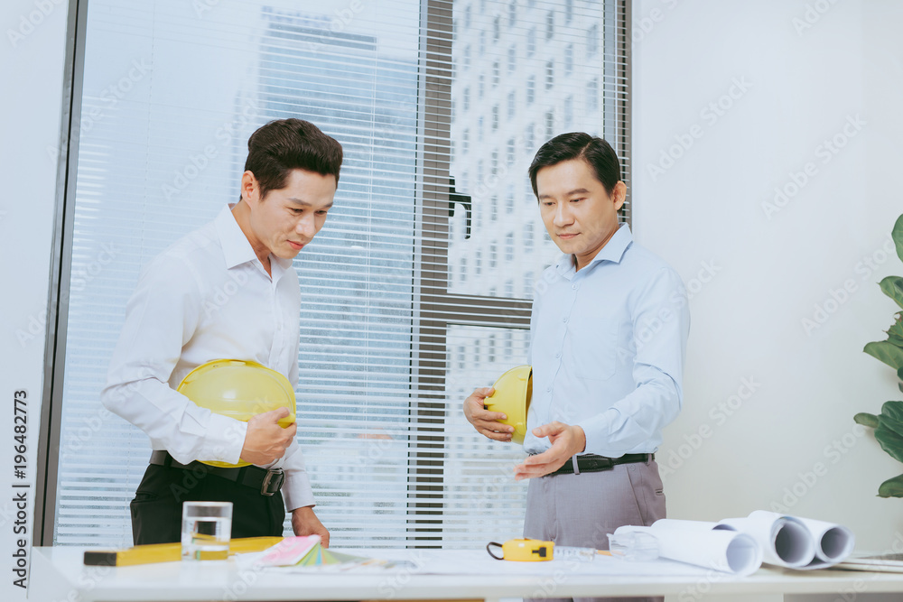 Architects engineer discussing at the table with blueprint of architectural project