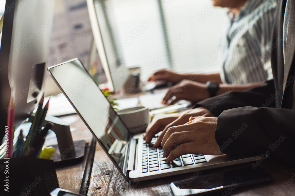 Hand of employees are working in the office. His computer is entering financial data.