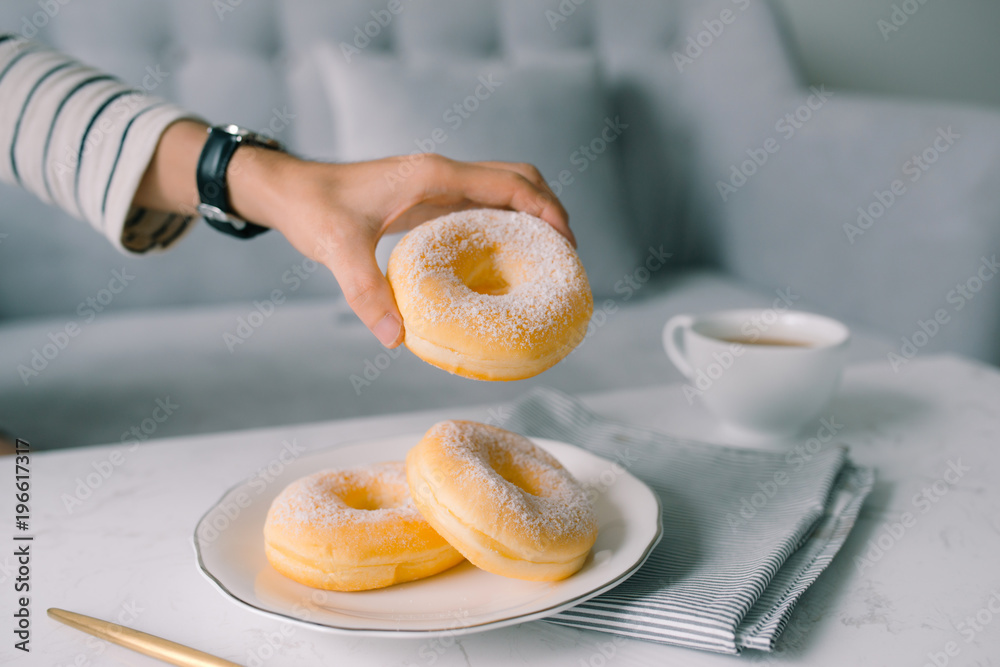 Food and Bakery, Hand Holding Delicious Fresh and Sweet Donut with Sugar Toppings on White Dish.