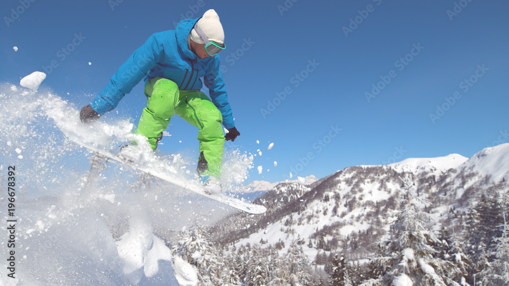 特写：职业单板滑雪运动员下坡并在高空跳跃。