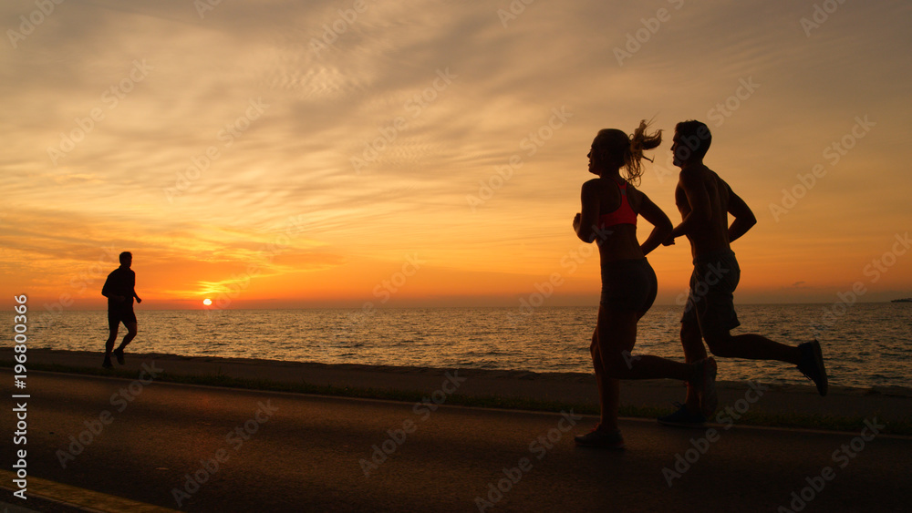 沉默：健康的人在夏日日落前沿着沉默的海洋道路奔跑。