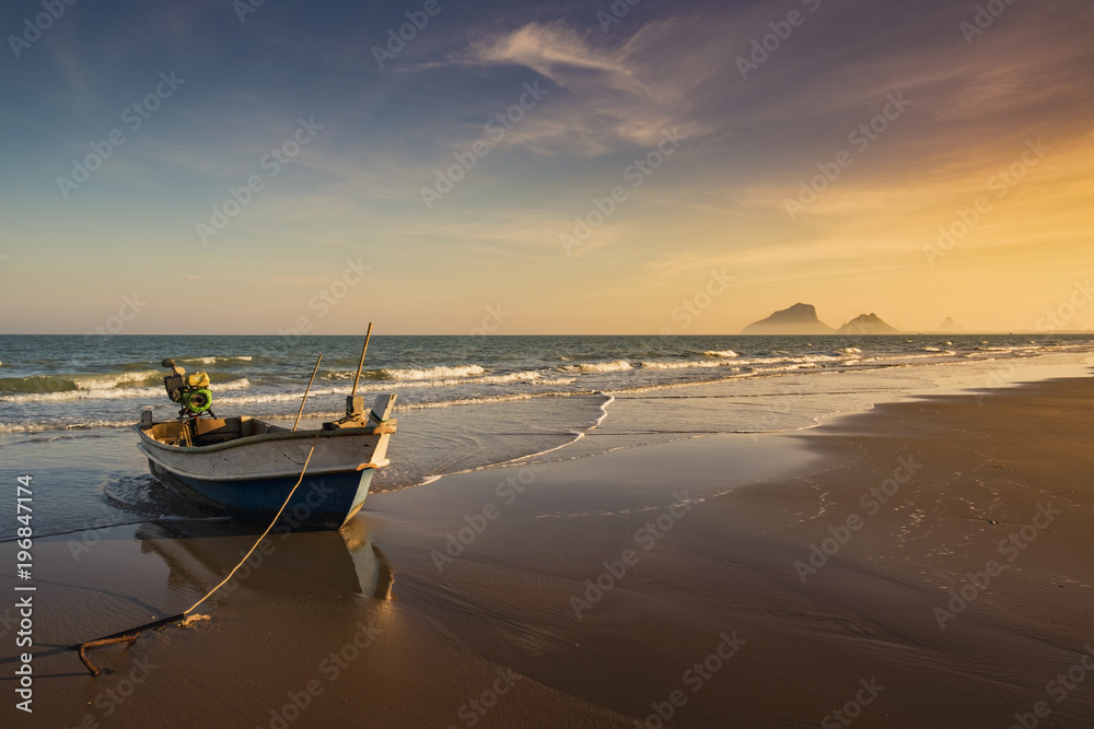 Sunset in Prachuab Khiri Khan, Thailand with golden sky, beach and fisherman boat.