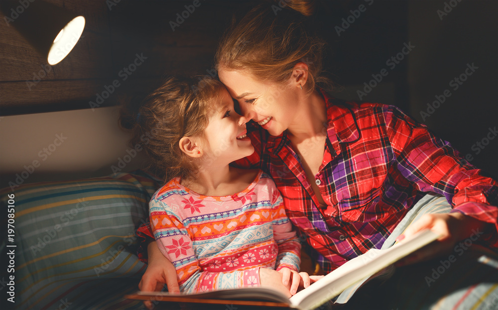 mother and child reading book in bed before going to sleep .