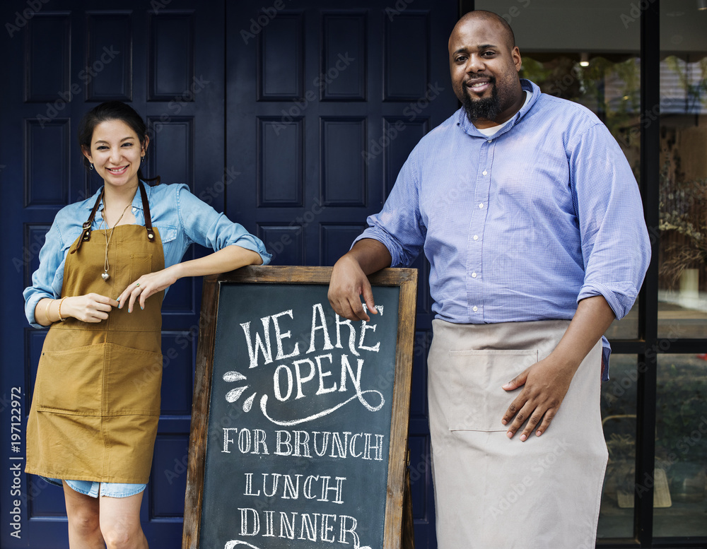 Cheerful business owners standing with open blackboard