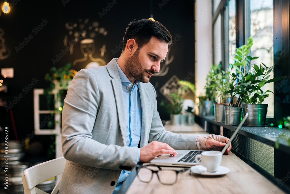 Young businessman working on laptop computer in modern cafe