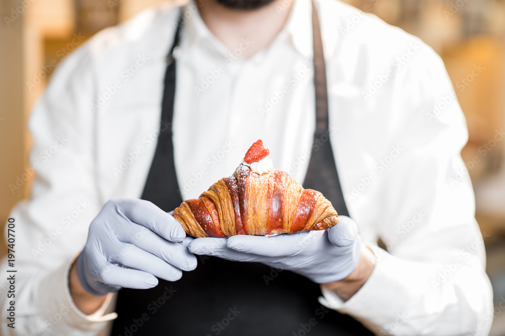 Holding delicious croissant with raspberry in the bakery store