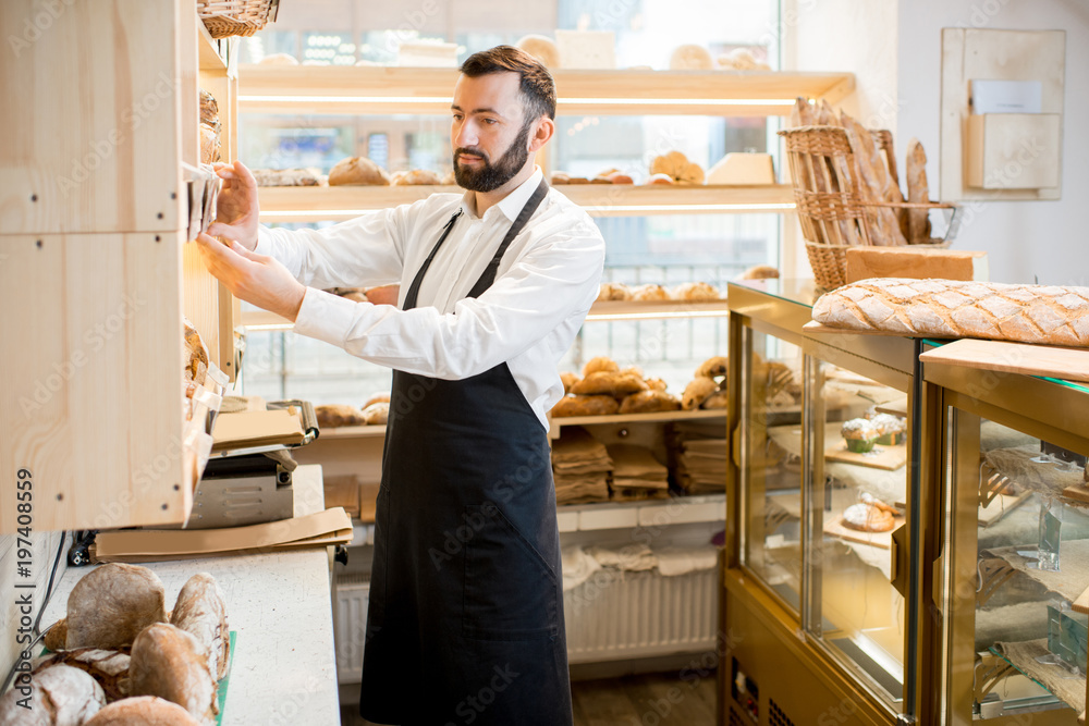 Seller making arrangements on the shelves in the store with bakery products