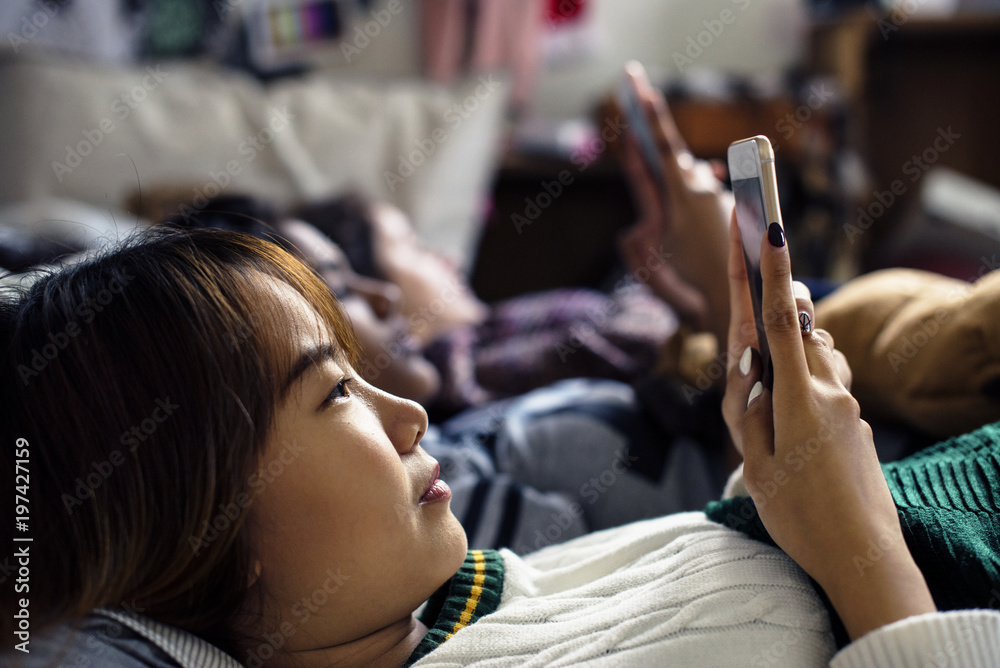 青少年女孩在床上使用智能手机参加睡眠派对