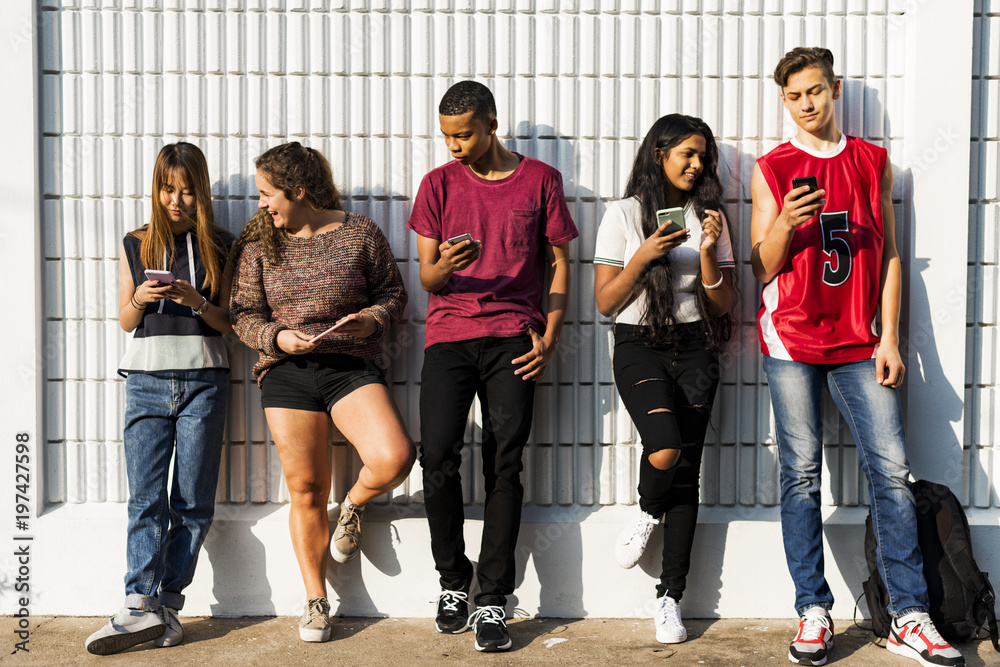 Group of young teenager friends chilling out together using smartphone social media concept