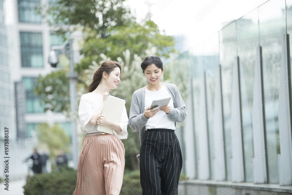 タブレットを眺めながら歩いている女性社員たち