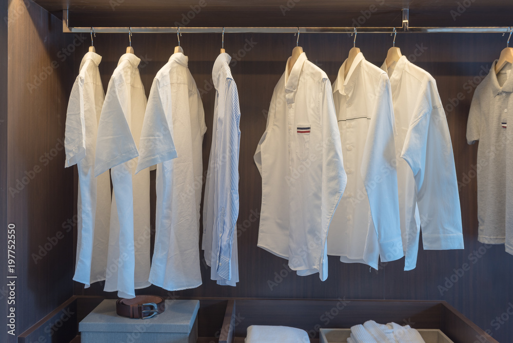 row of white shirts on rail in wooden closet