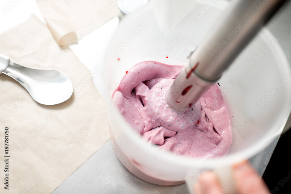 Mixing milk with sugar and berries for ice cream production