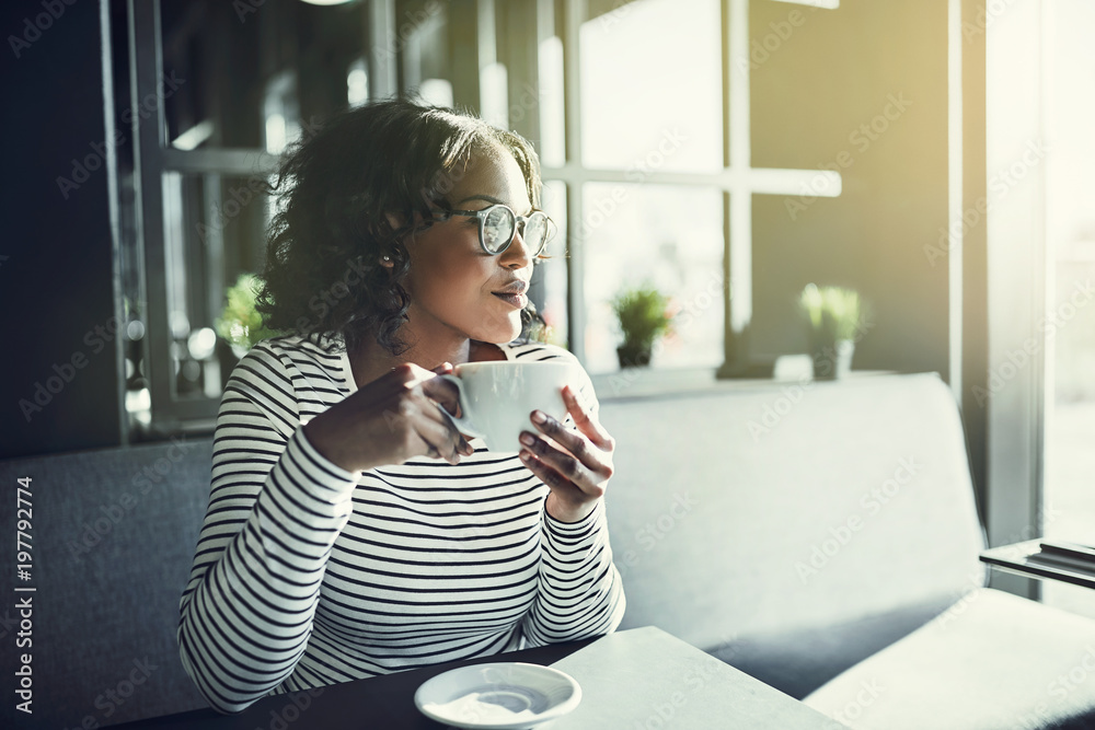 Young African woman sitting in a cafe drinking coffee