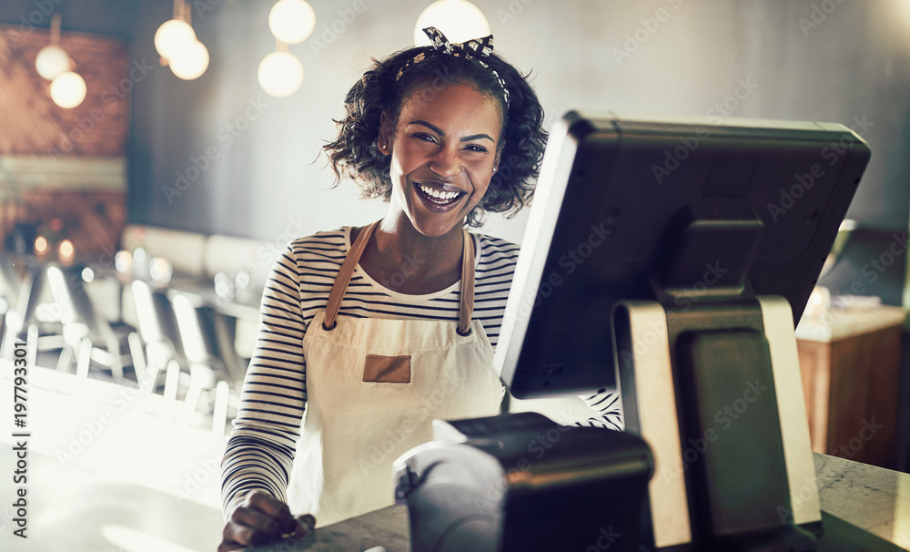 African waitress laughing while working in a trendy restaurant