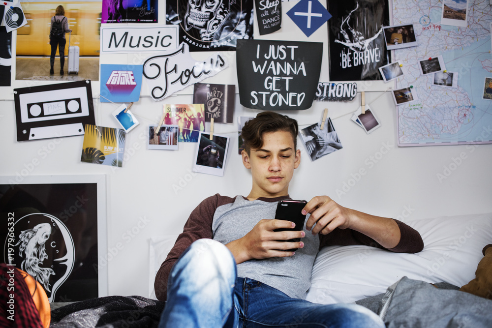 Teenage boy using smartphone in a bedroom social media concept