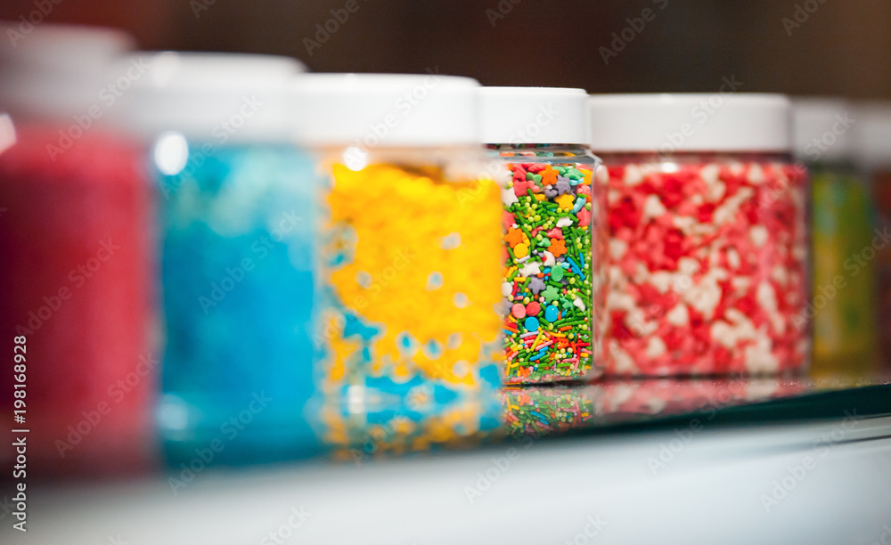 Jars with colorful candies on shelf at confecionery shop