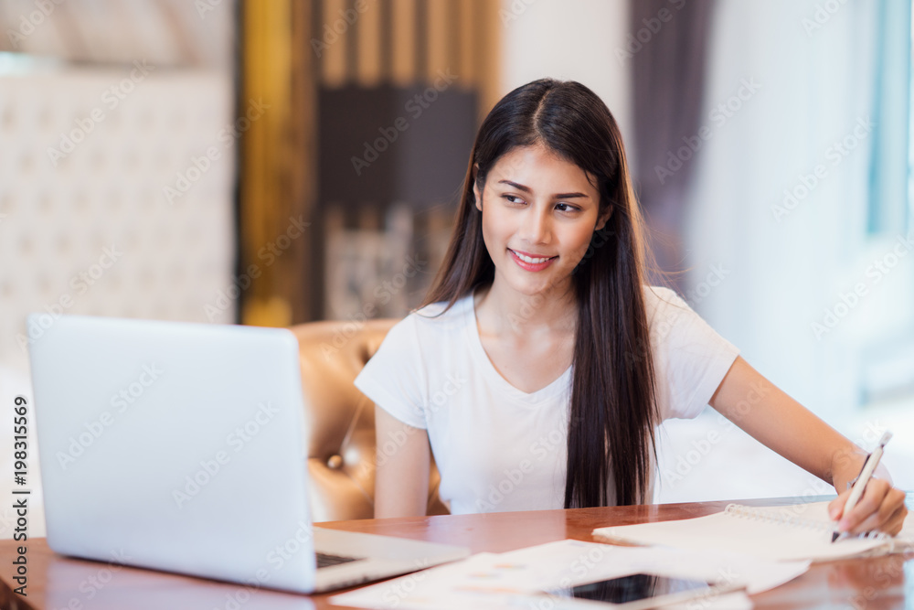 Asian lady student do home work on the desk with computer notebook