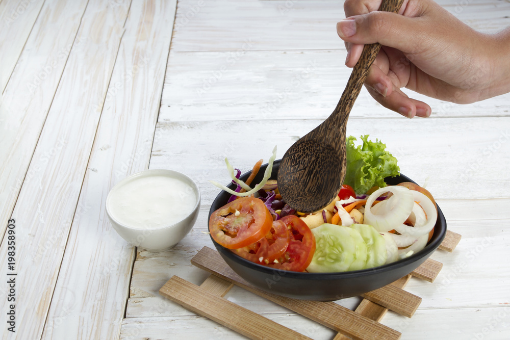 close up of hand holding spoon with salad