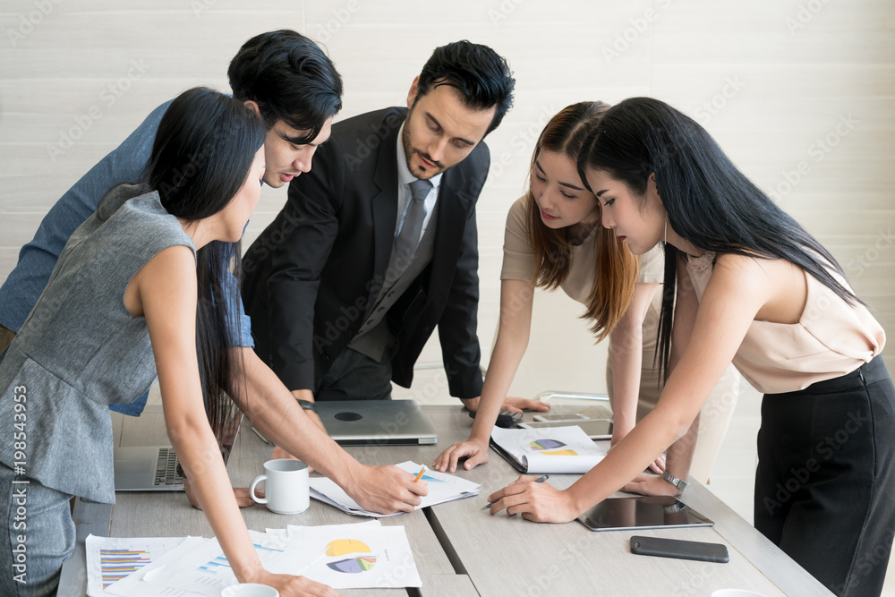 Smart manager explaining internal meeting to his project team in modern office. The multi ethnic bus