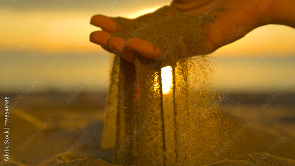 CLOSE UP: Unrecognizable woman grabs a handful of dry sand and lets it fall.