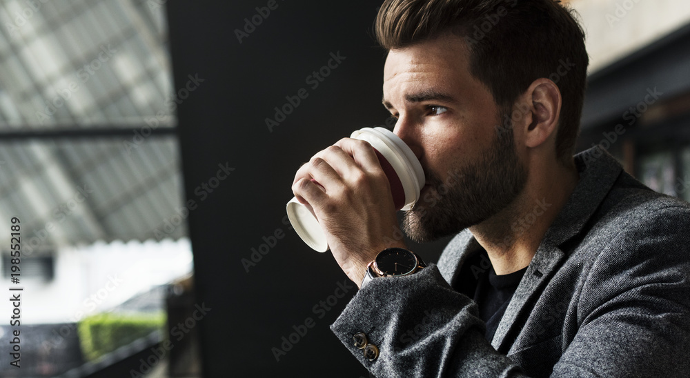 Side view of mna drinking hot coffee