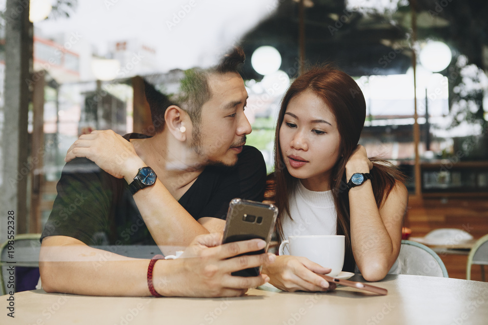 Couple using a phone at a cafe