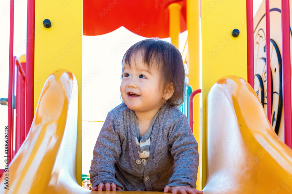 Mixed race toddler boy playing on a slide at a playground