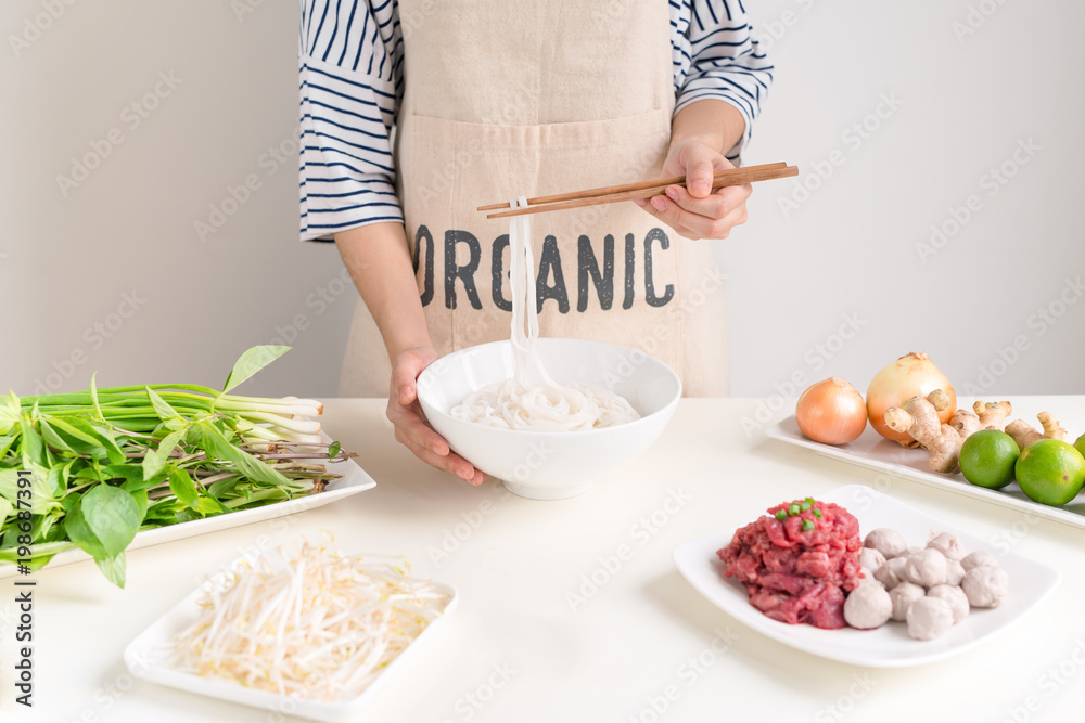 女厨师准备越南传统汤Pho bo，配香草、肉和米粉