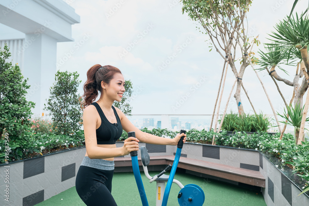 亚洲女性在户外健身房操场设备锻炼