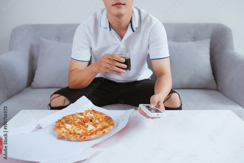 男人看电视，用软饮料吃披萨。特写。坐在沙发上