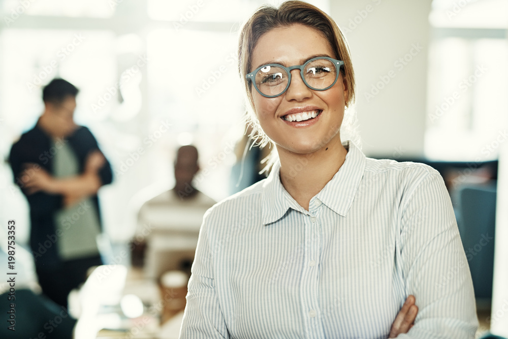 Smiling businesswoman in an office with colleagues in the background