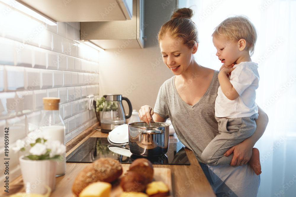 preparation of family breakfast. mother and baby son cook porridge in morning