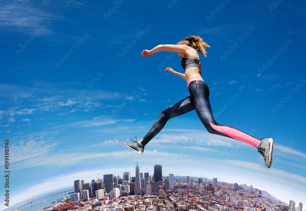 Jumping fit girl across blue sky