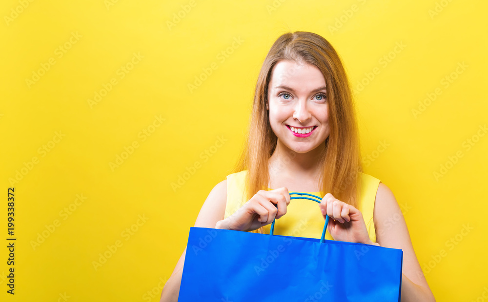 Young woman holding a shopping bag on a yellow background