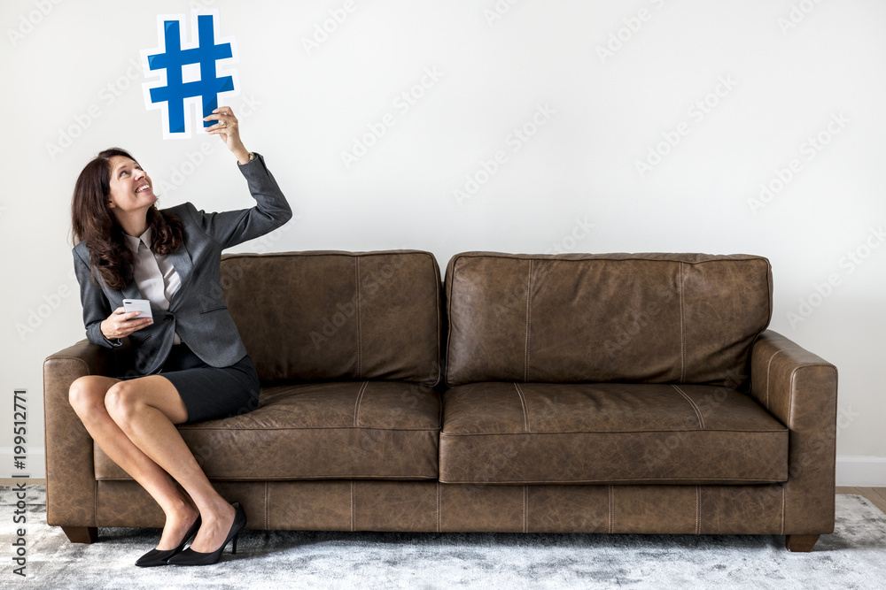 Businesswoman sitting on couch holding icon