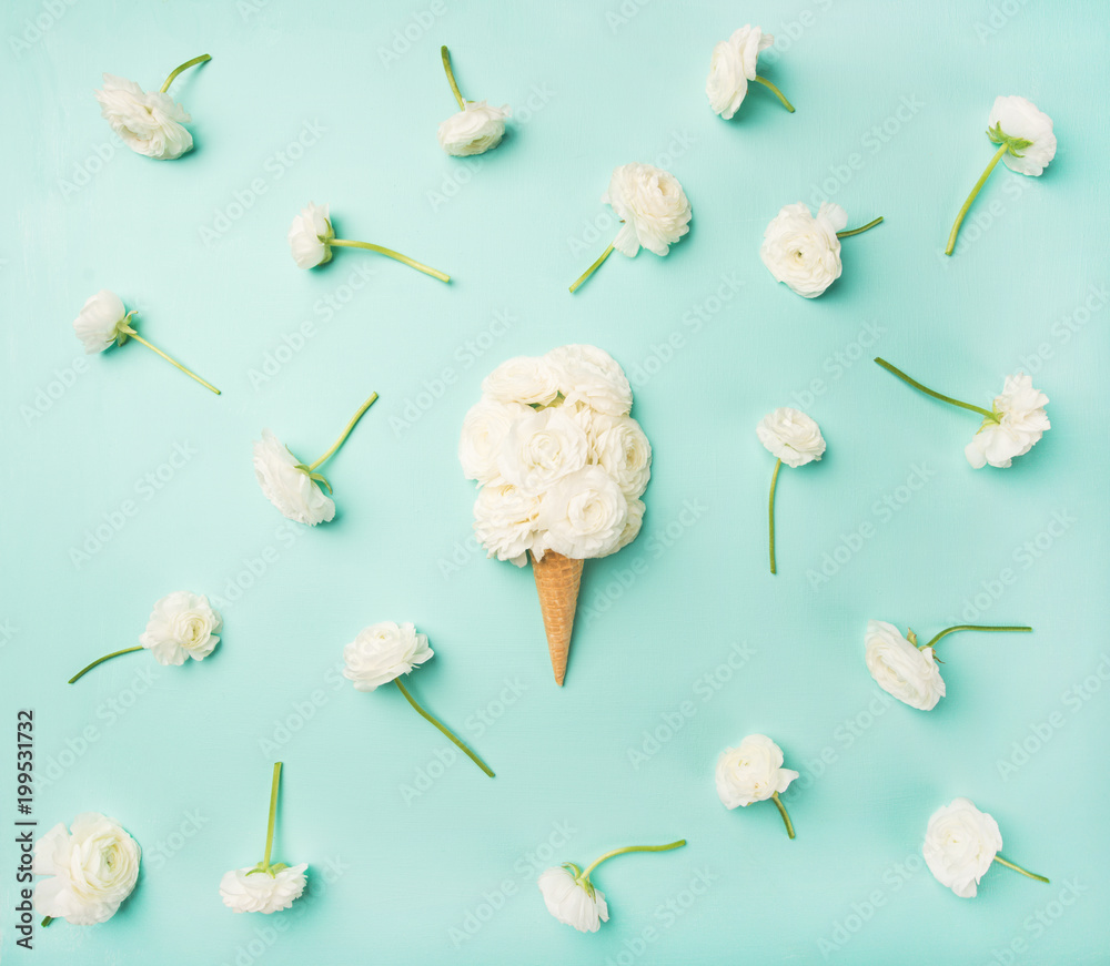 Flat-lay of waffle sweet cone with white buttercup flowers over light blue background, top view. Spr