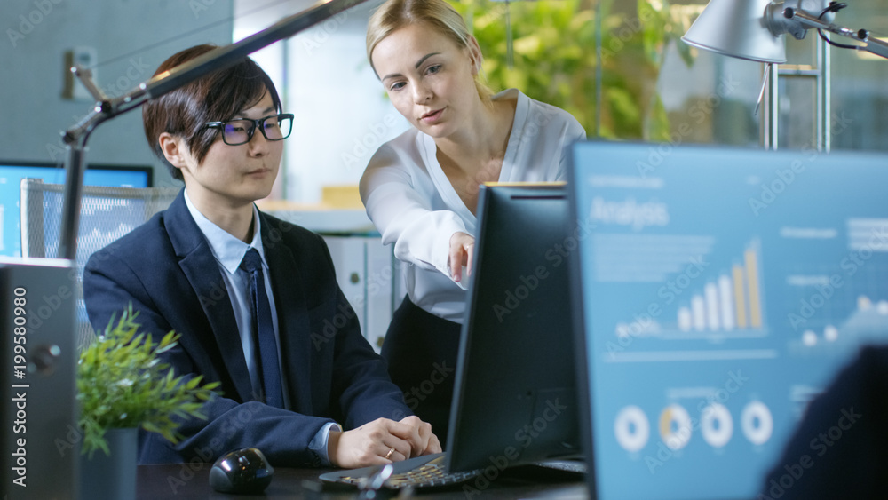 In the Office Young Businesswoman Sitting at Her Desk Talks with Her Manager, theyre pointing at Co