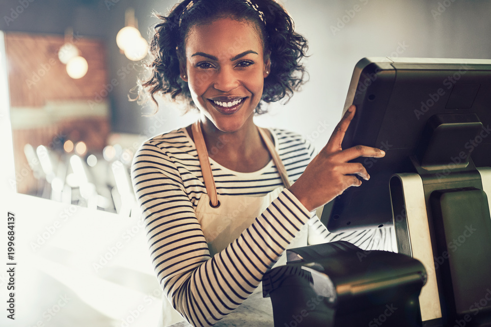 Smiling young African waitress working in a trendy restaurant