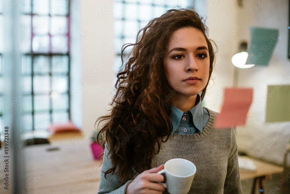 富有创意的女商人在玻璃墙上读便签。