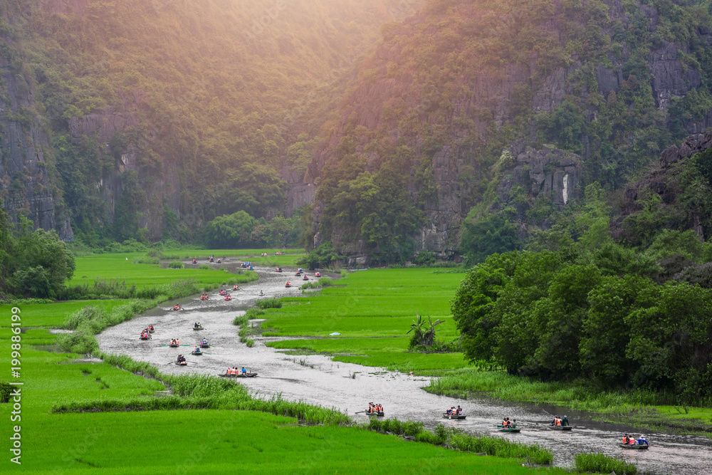 鸟瞰图游客乘船沿着Ngo Dong河旅行，并拍摄Tam Coc，R的照片