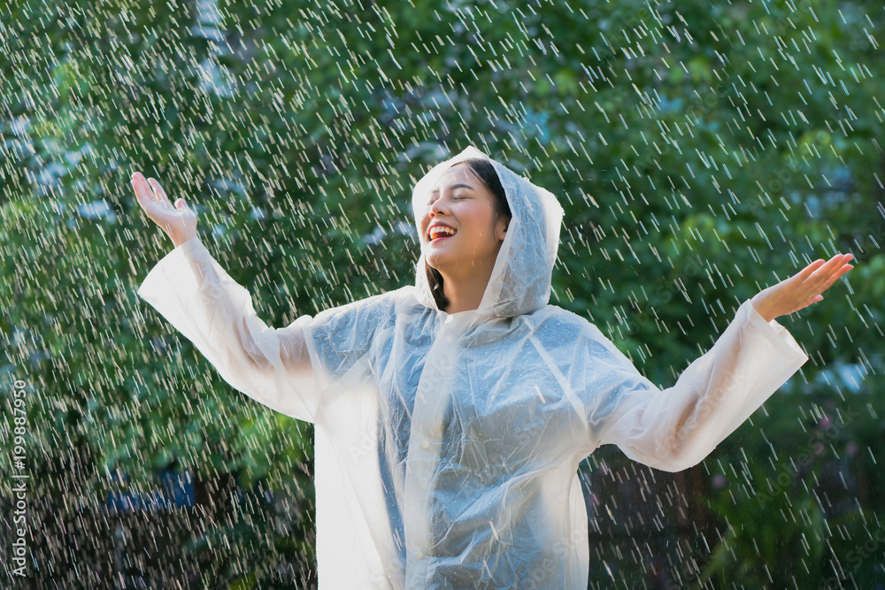 雨天亚洲女人在户外穿着雨衣。她很开心。