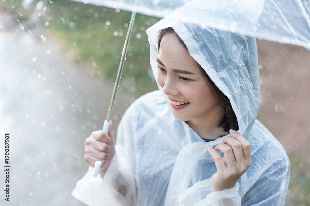 雨天亚洲女人在户外穿着雨衣。她很开心。