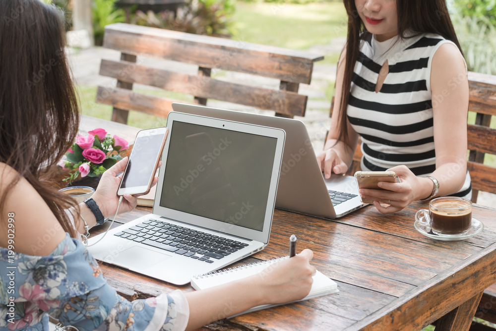 Two Beautiful freelance woman work with laptop and smartphone in coffee shop, modern generation life